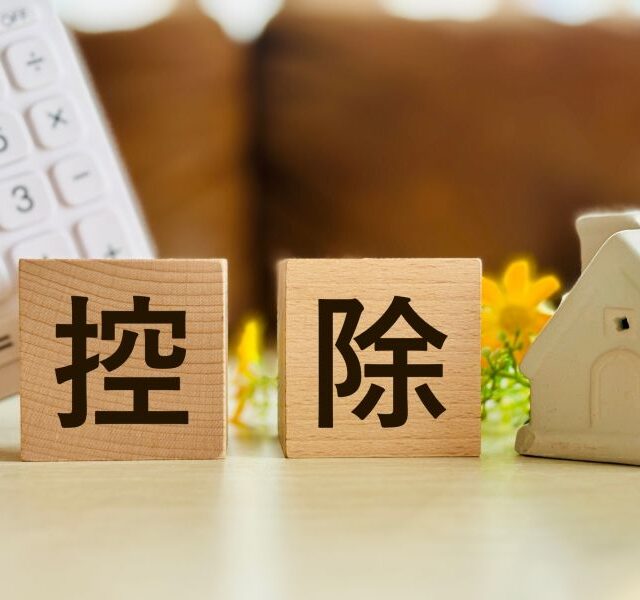 家のオブジェと電卓、積み木に書かれた控除の文字