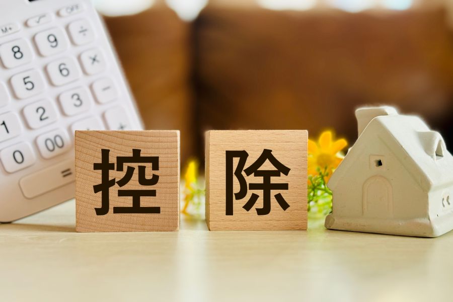 家のオブジェと電卓、積み木に書かれた控除の文字